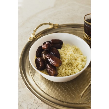 Semoule de couscous maison préparée dans un couscoussier traditionnel, accompagnant méchoui d’agneau et de veau.